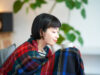 Young woman wearing a blanket and holding a mug